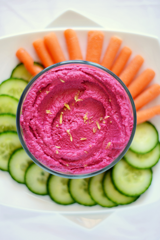 Sliced veggies and bowl of Roasted Beet Hummus topped with lemon zest