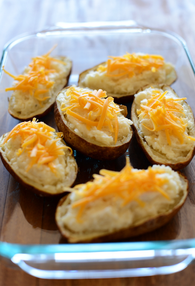 Pan of Cauliflower Twice-Baked Potatoes topped with shredded cheddar cheese
