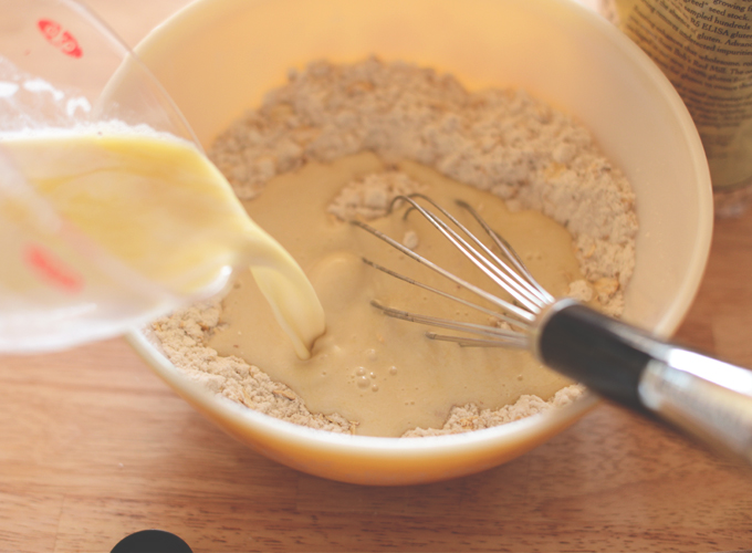 Pouring wet ingredients into dry for our Vegan Oat Waffles recipe