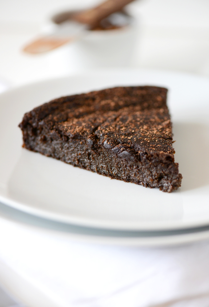 Plate with a slice of Fudgy Gluten-Free Chocolate Cake sprinkled with cocoa powder