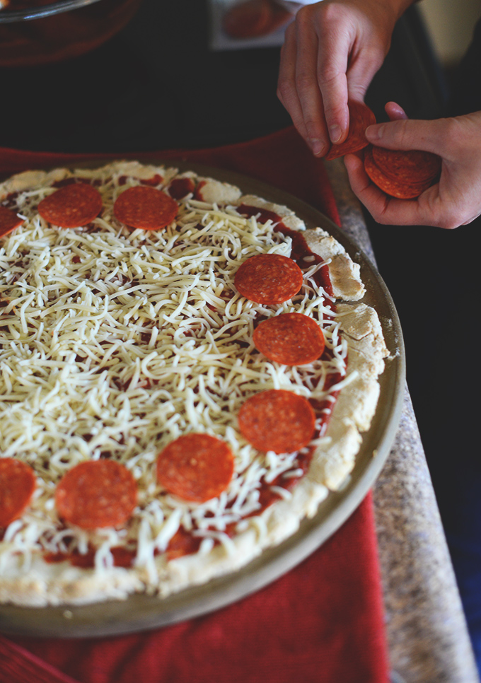 Adding pepperoni slices to a homemade pizza