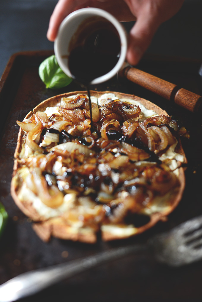 Drizzling balsamic reduction onto our Caramelized Onion and Goat Cheese Pizza