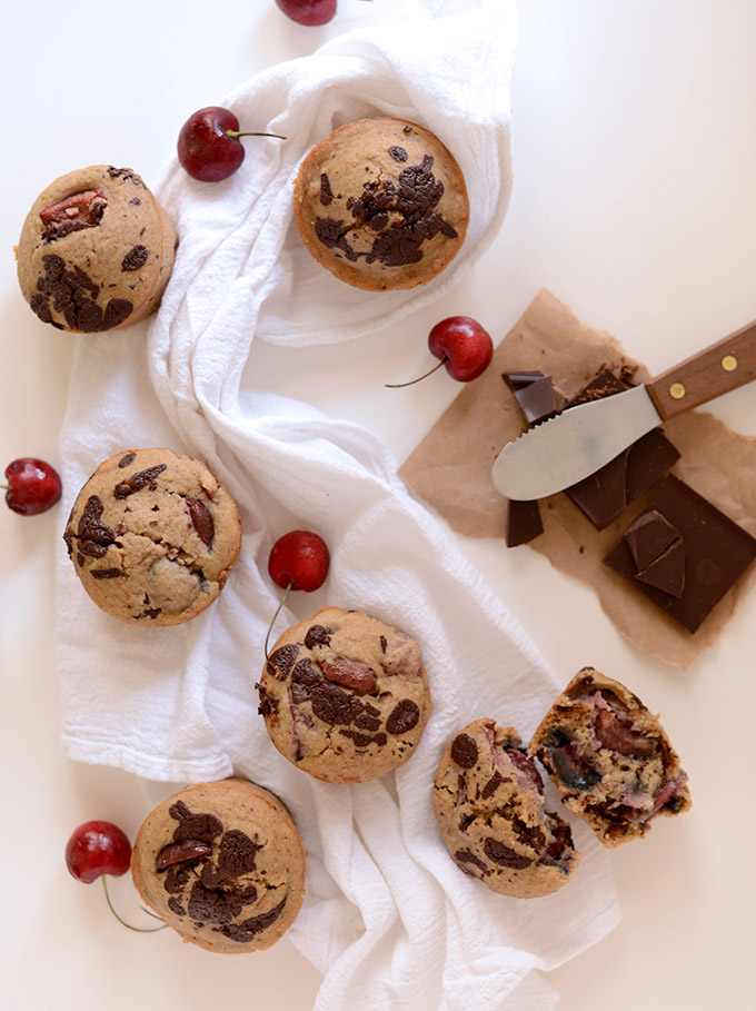 Batch of our Dark Chocolate Cherry Muffins recipe alongside fresh cherries and dark chocolate