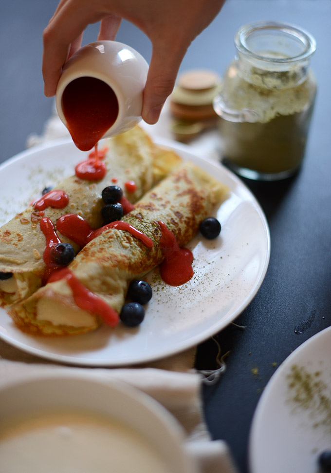 Pouring homemade Strawberry Sauce over a plate of Green Tea Crepes