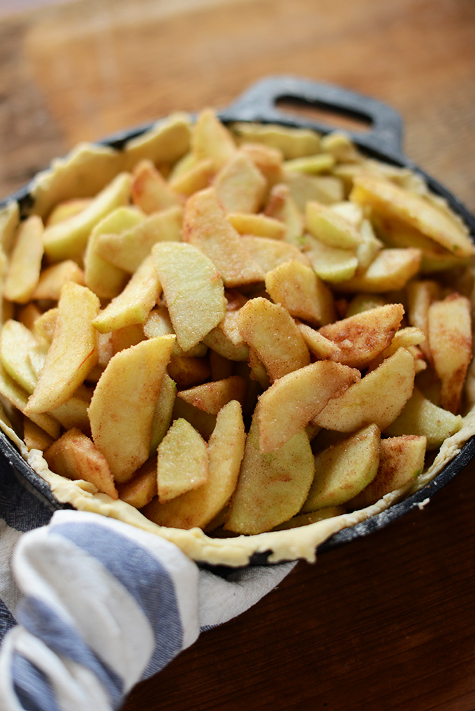 Cast-iron skillet filled with crust and apples for homemade apple pie