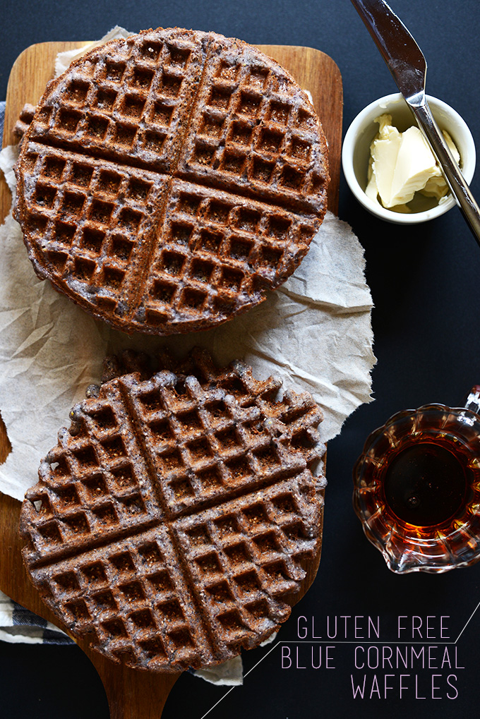 Freshly cooked Gluten-Free Blue Cornmeal Waffles alongside vegan butter and maple syrup