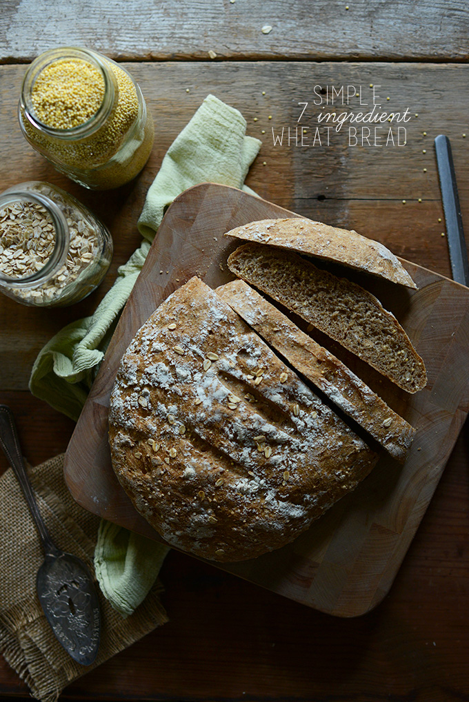 Partially sliced loaf of whole grain Wheat Bread with jars of oats and millet