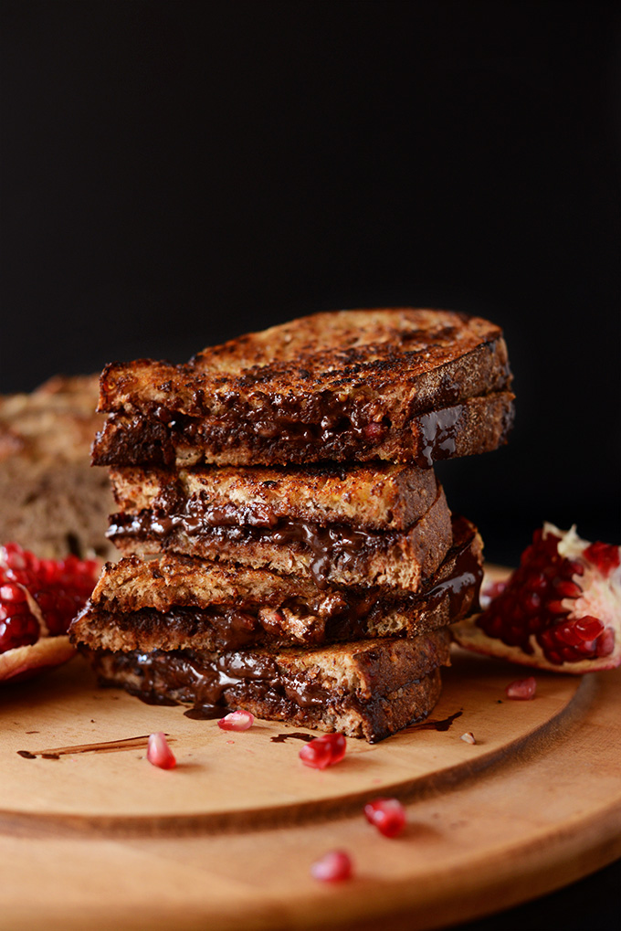 Grilled Almond Butter, Dark Chocolate, Pomegranate Sandwiches piled high on a cutting board