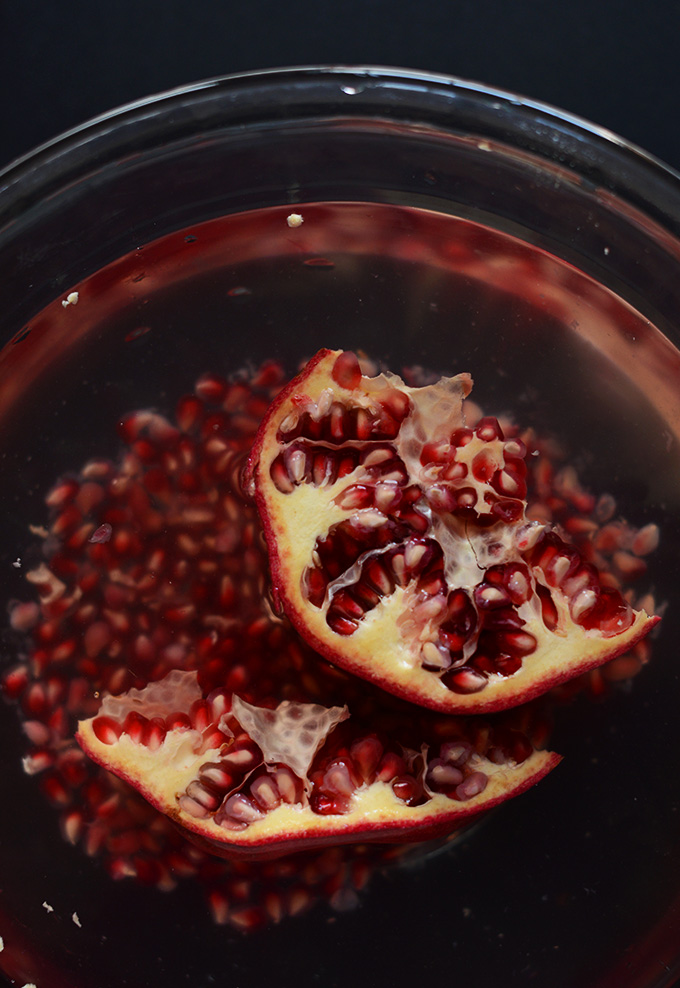 Bowl of pomegranate seeds and fresh pomegranate ready to have its seeds removed