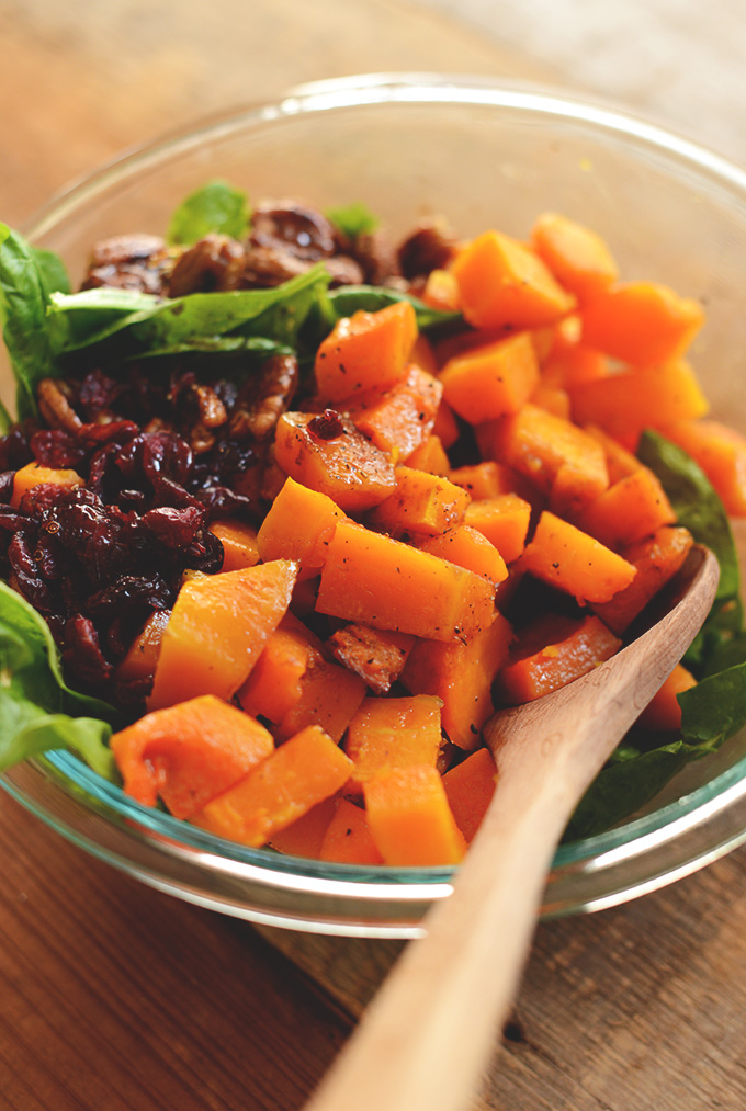 Bowl of Roasted Butternut Squash Salad with spinach, cranberries, and caramelized pecans