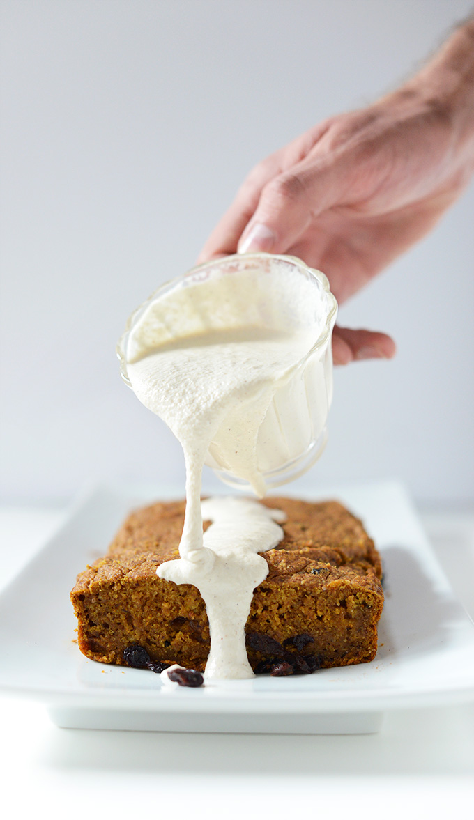 Drizzling Maple Cashew Frosting onto a loaf of Vegan Pumpkin Bread