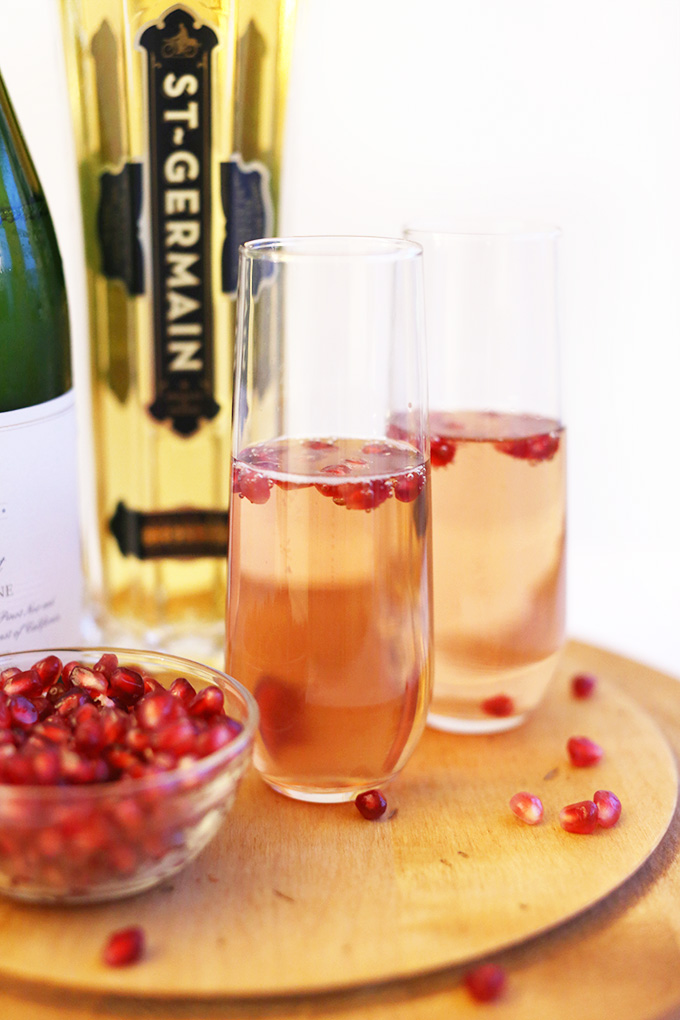 Two tall glasses of St. Germain Spritzers with fresh pomegranate seeds