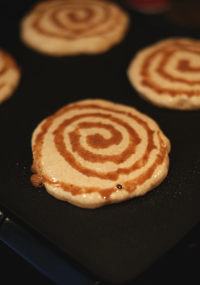 Cooking Vegan Cinnamon Roll Pancakes on a griddle