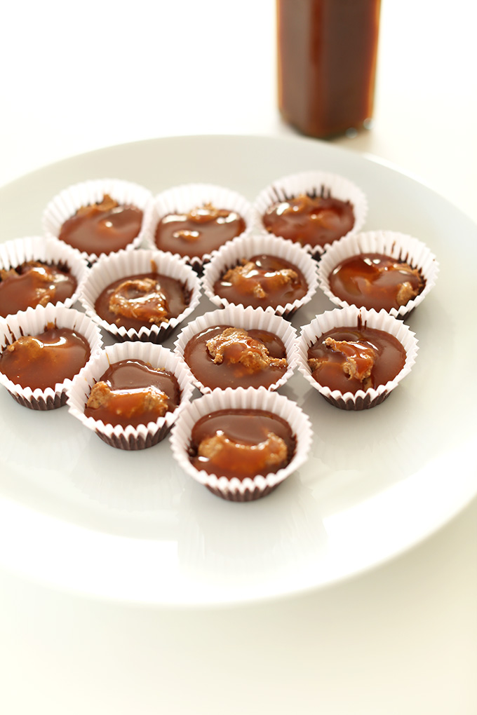 Plate of almond butter cups in process showing the chocolate, almond butter, and caramel layers 