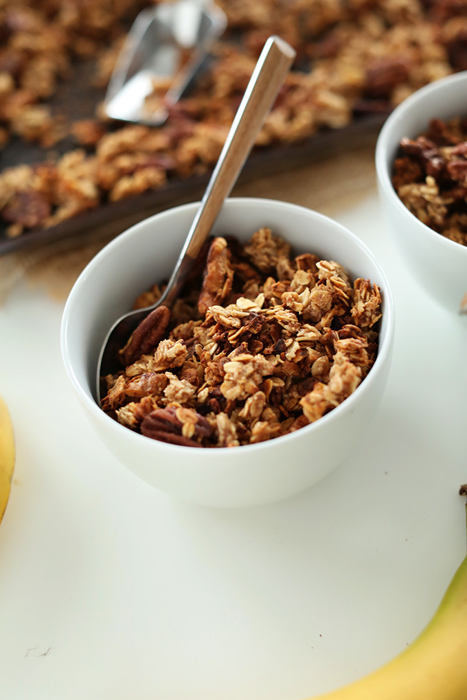 Serving bowls and baking sheet with Banana Bread Granola for a delicious vegan breakfast