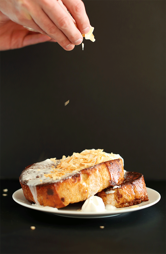 Sprinkling freshly toasted coconut flakes onto slices of Coconut Cream Pie French Toast