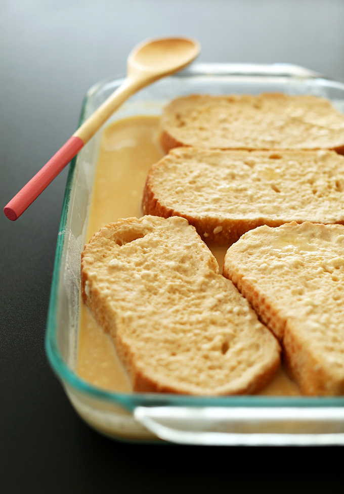 Slices of bread resting in batter for Overnight French Toast