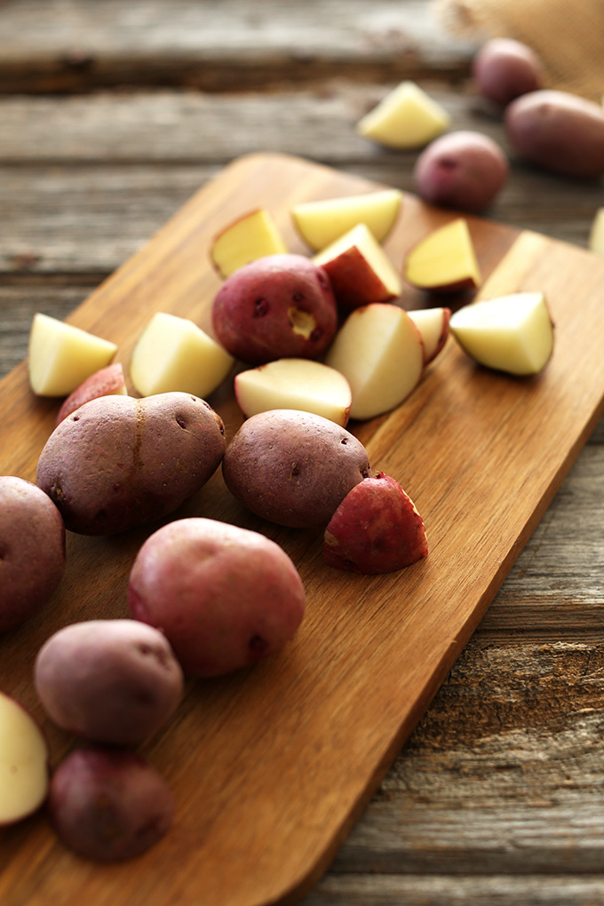 Cutting board filled with an assortment of chopped and whole red skin potatoes