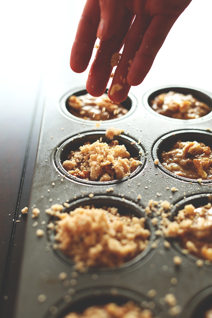 Sprinkling crumble topping onto a batch of our Vegan Banana Muffins recipe