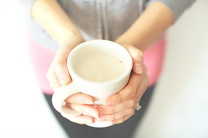 Holding a mug of our homemade vegan Ginger Tea Latte