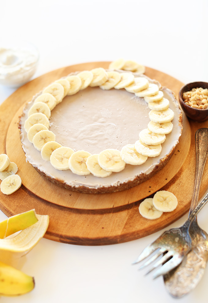Cutting board with Creamy Vegan Banana Cream Pie topped with a ring of banana slices