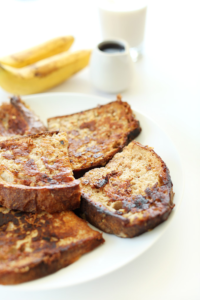 Plate of Vegan Banana French Toast with nut milk, bananas, and syrup in the background