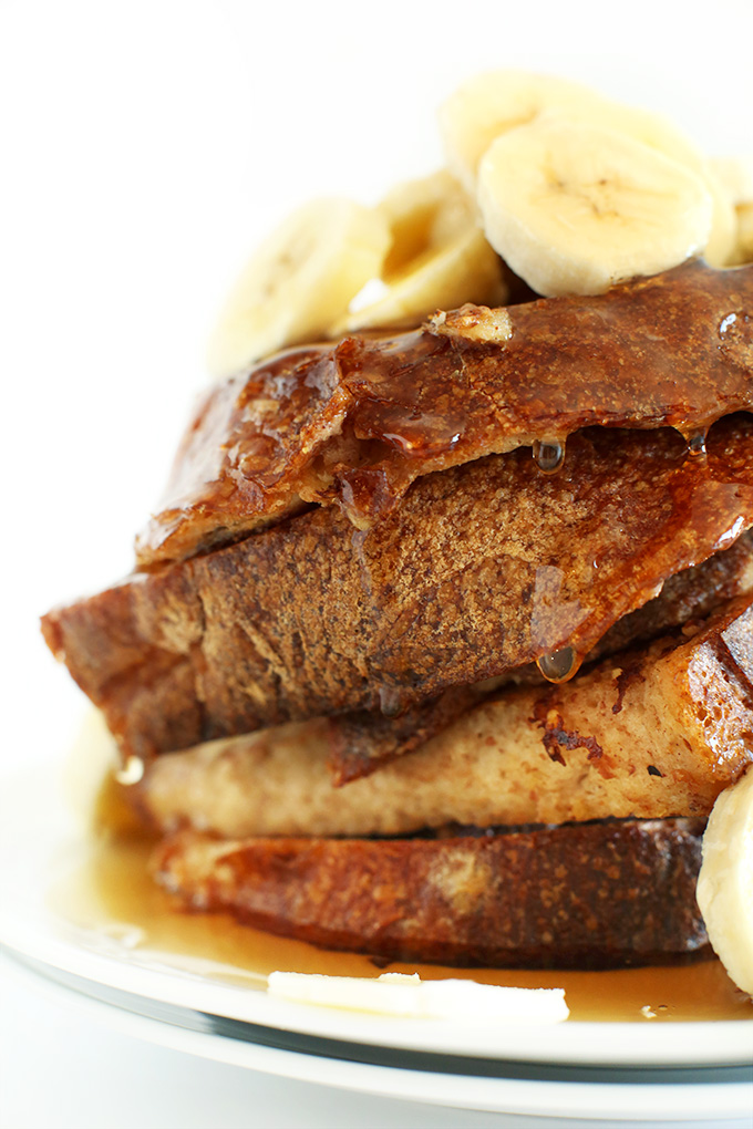Stack of Vegan Banana French Toast with sliced bananas and maple syrup