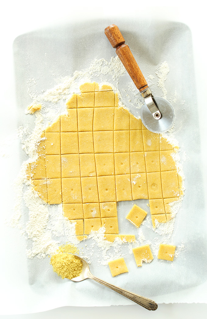 Using a pizza cutter to cut homemade Vegan Cheez Itz on a floured surface