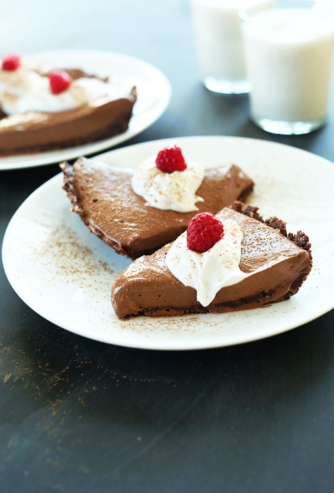 Plates with slices of Vegan Chocolate Silk Pie topped with coconut whip and raspberries
