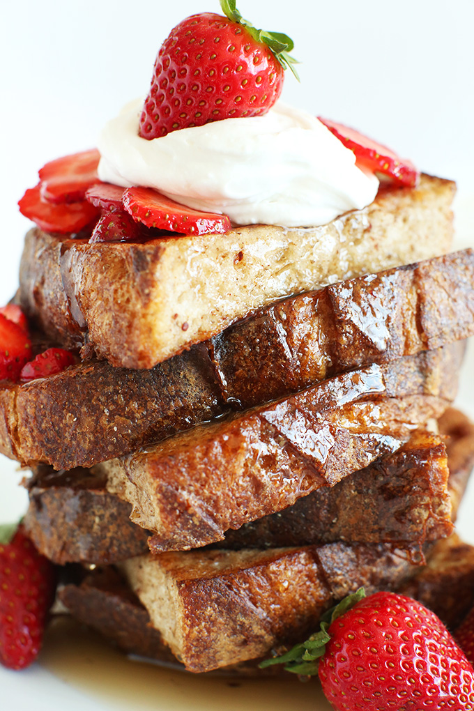 Side view of a stack of Vegan French Toast slices with fresh strawberries and coconut whipped cream