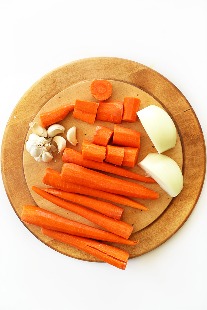 Cutting board with carrots, onion, and garlic for making delicious soup