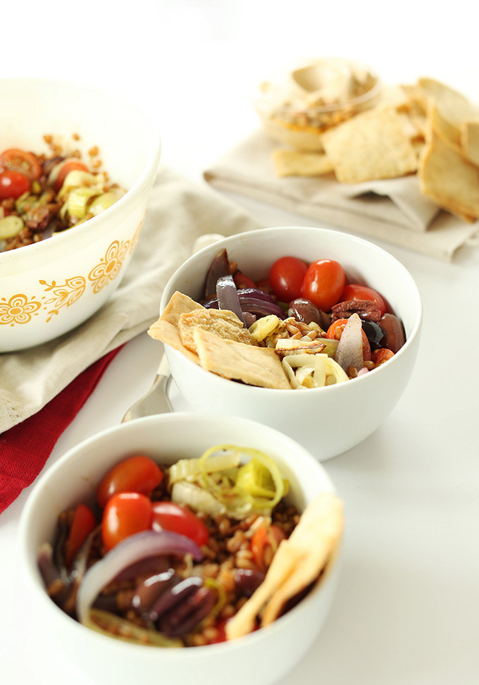 Bowls of Mediterranean Wheat Berry Salad alongside pita chips and hummus