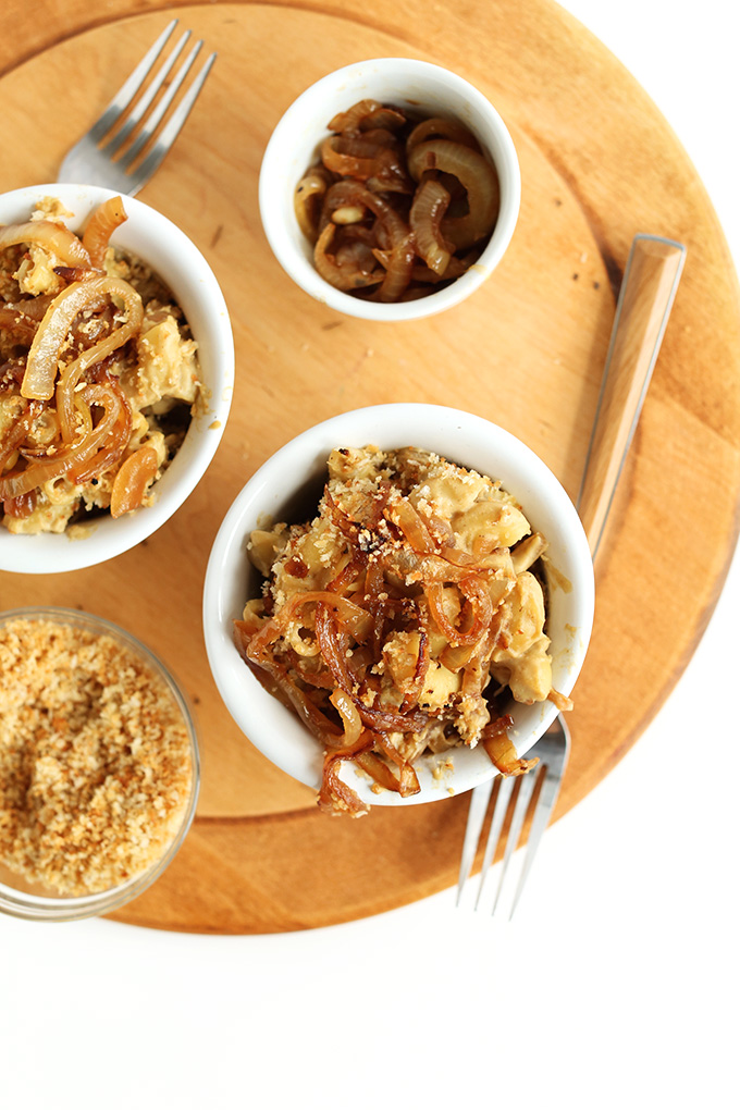 Bowls of Caramelized Onion Mac n Cheese with sides of breadcrumbs and extra caramelized onions