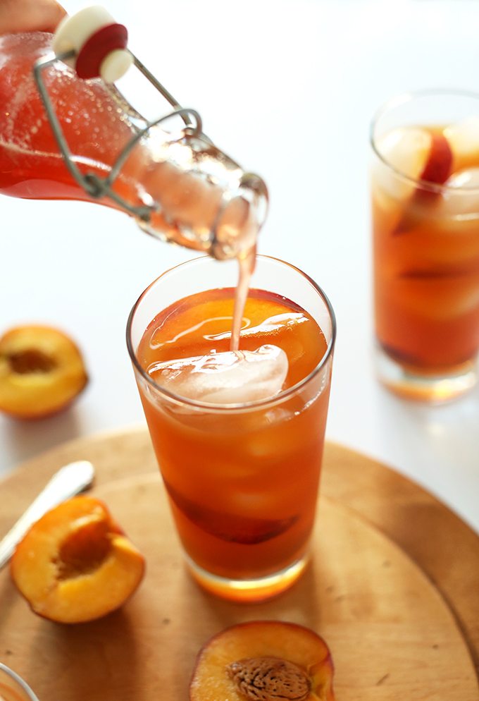 Pouring Peach Iced Tea into a glass of ice cubes and peach slices