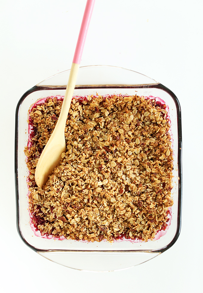 Using a wooden spoon to grab a serving of our Easy Vegan Raspberry Rhubarb Crisp