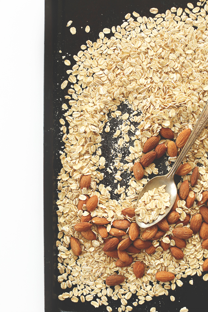 Oats and almonds on a baking sheet for making easy Super Seedy Granola Bars