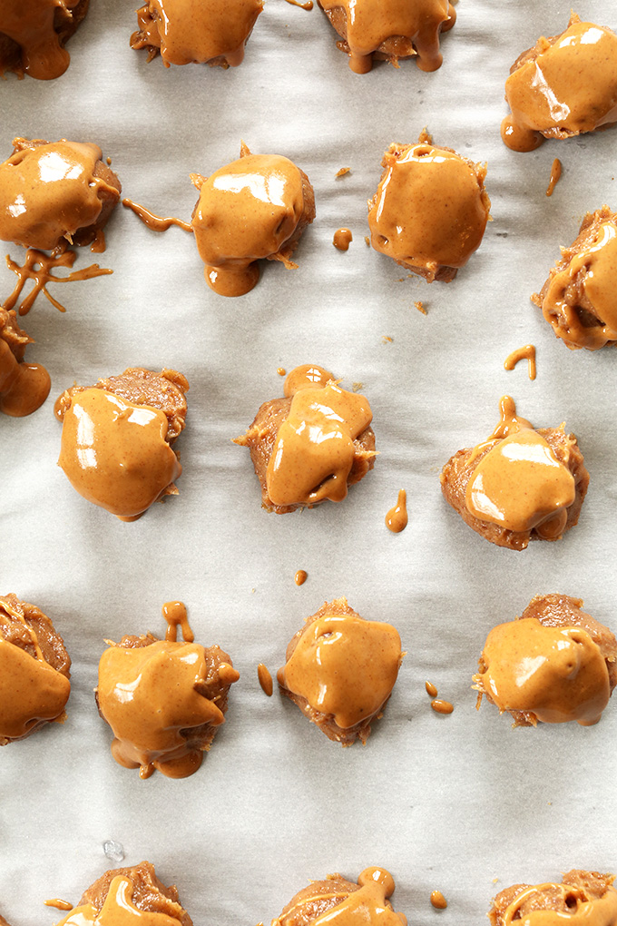 Parchment-lined baking sheet with Vegan Salted Caramel Balls topped with peanut butter