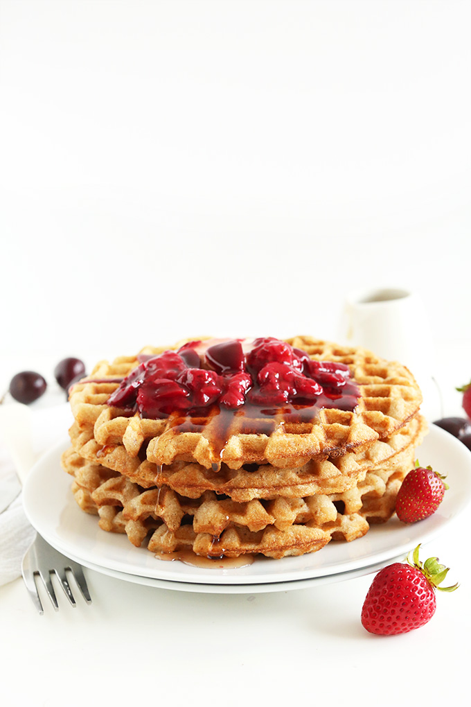Stack of gluten-free oatmeal waffles with fruit compote and maple syrup