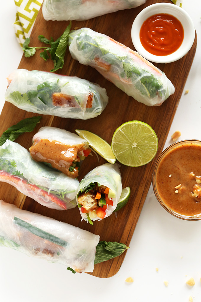 Wood cutting board filled with Vietnamese Spring Rolls and dipping sauce for a delicious vegan snack