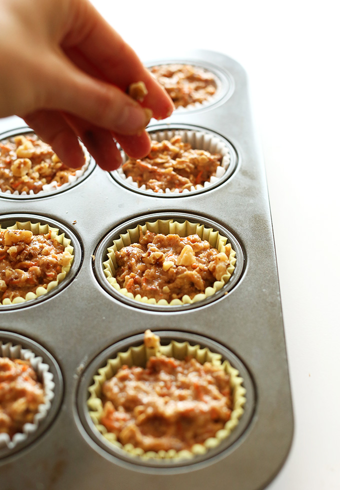 Sprinkling walnuts onto Vegan Gluten-Free Carrot Muffins