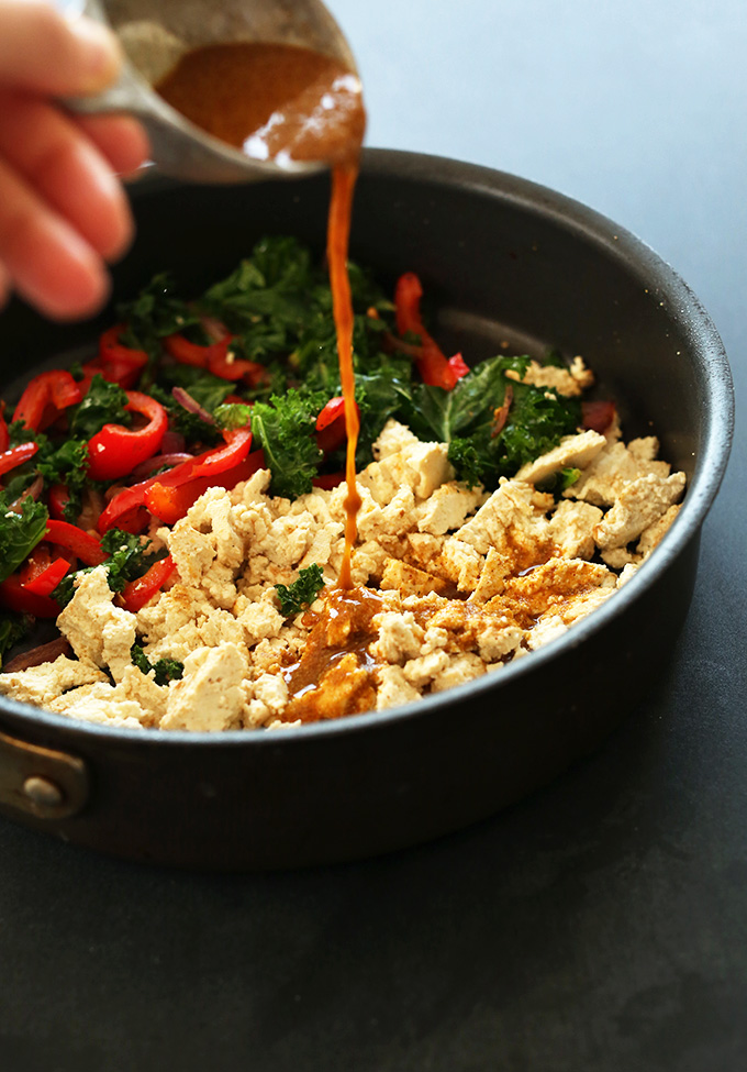 Pouring spice mix into a skillet for our Easy Tofu Scramble recipe