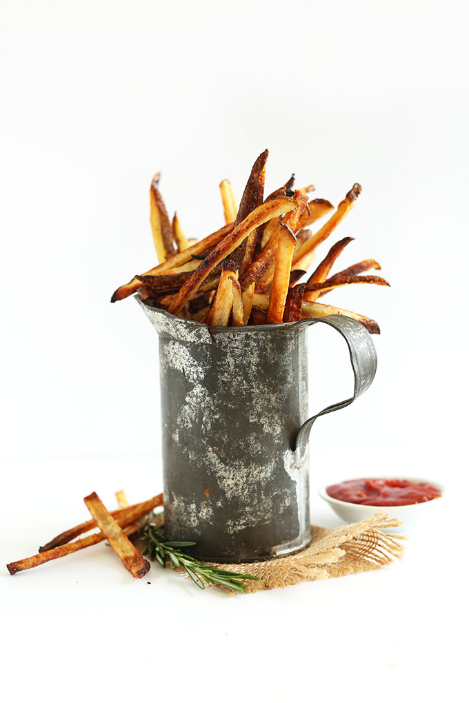 Tin container filled with simple vegan matchstick fries and a bowl of homemade ketchup
