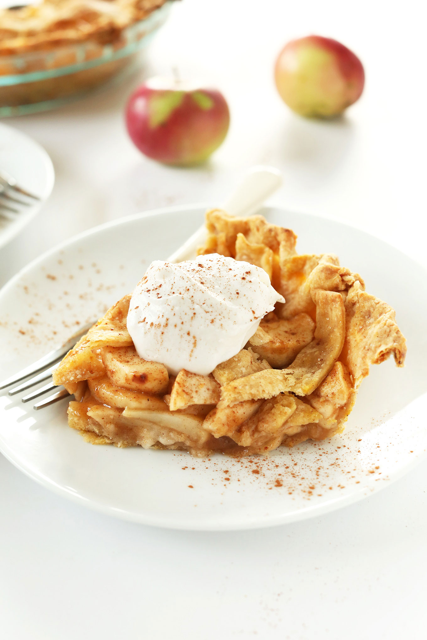 Side view of a slice of apple pie topped with coconut whip