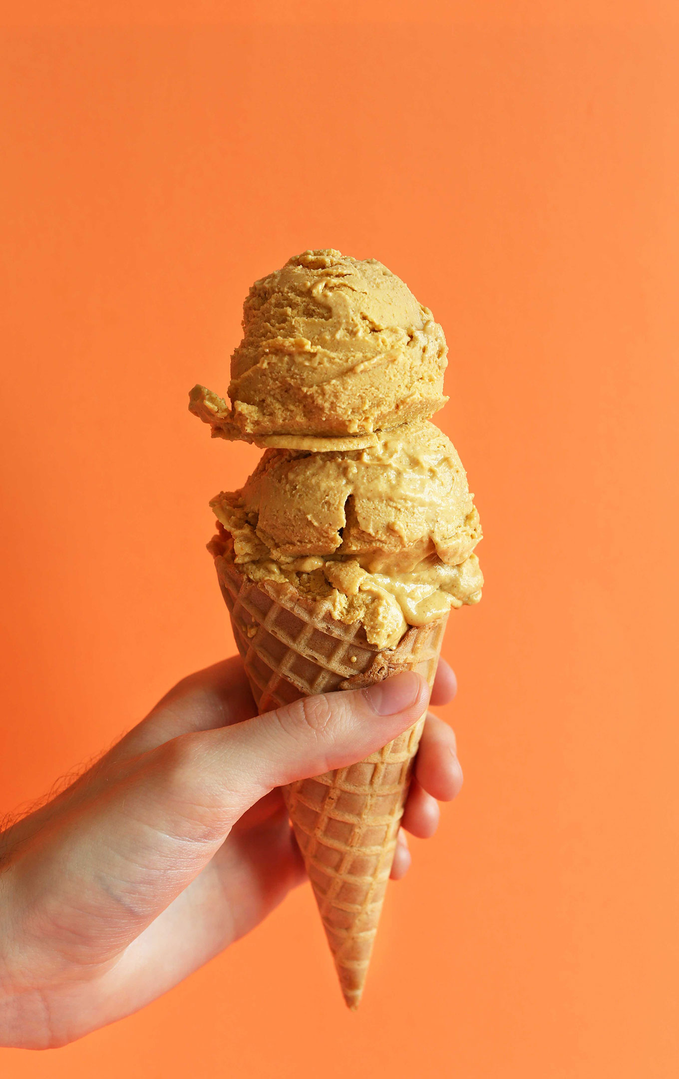 Holding up a cone with scoops of Creamy Pumpkin Pie Ice Cream