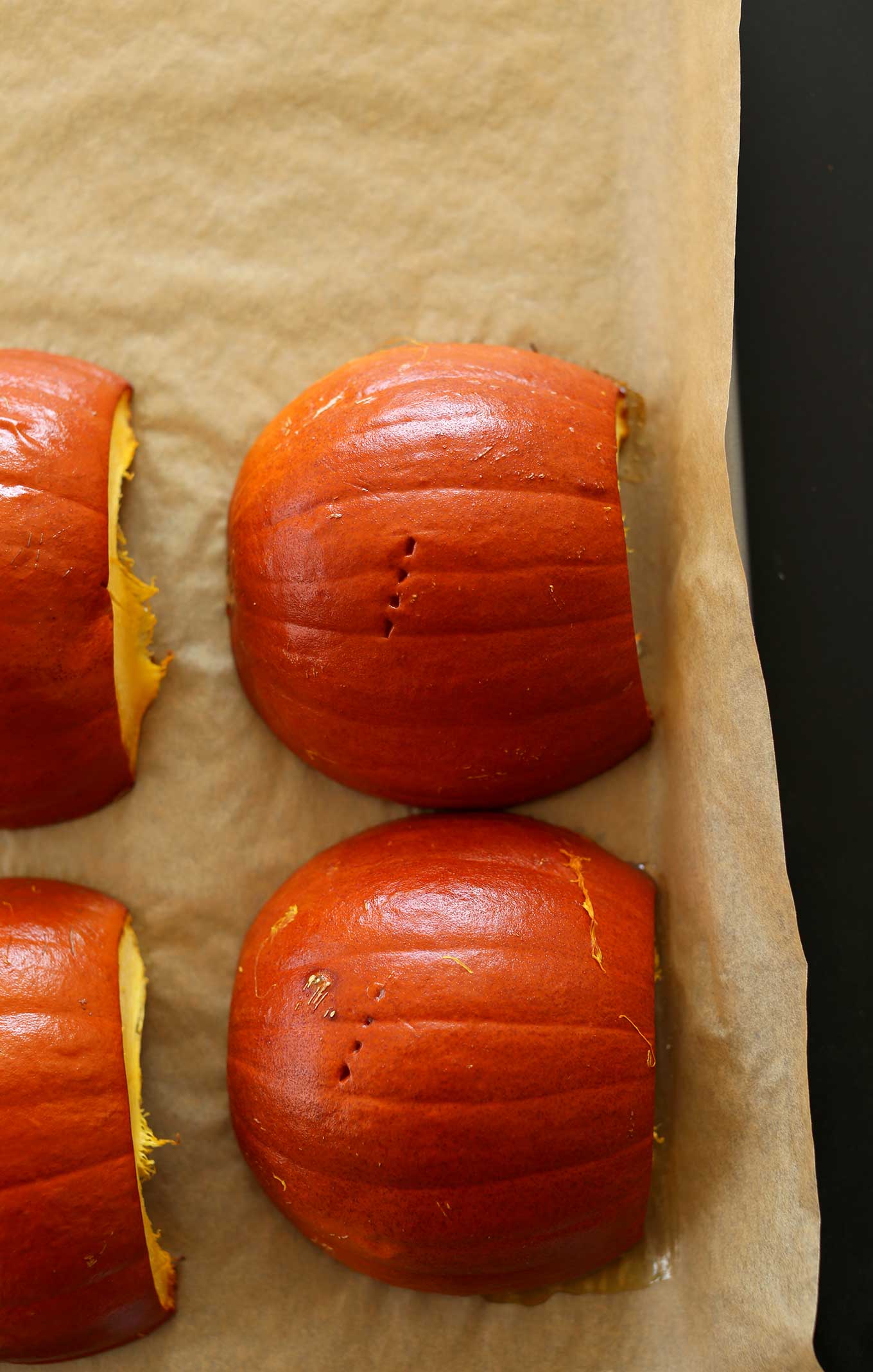 Freshly roasted sugar pumpkins on a parchment-lined baking sheet