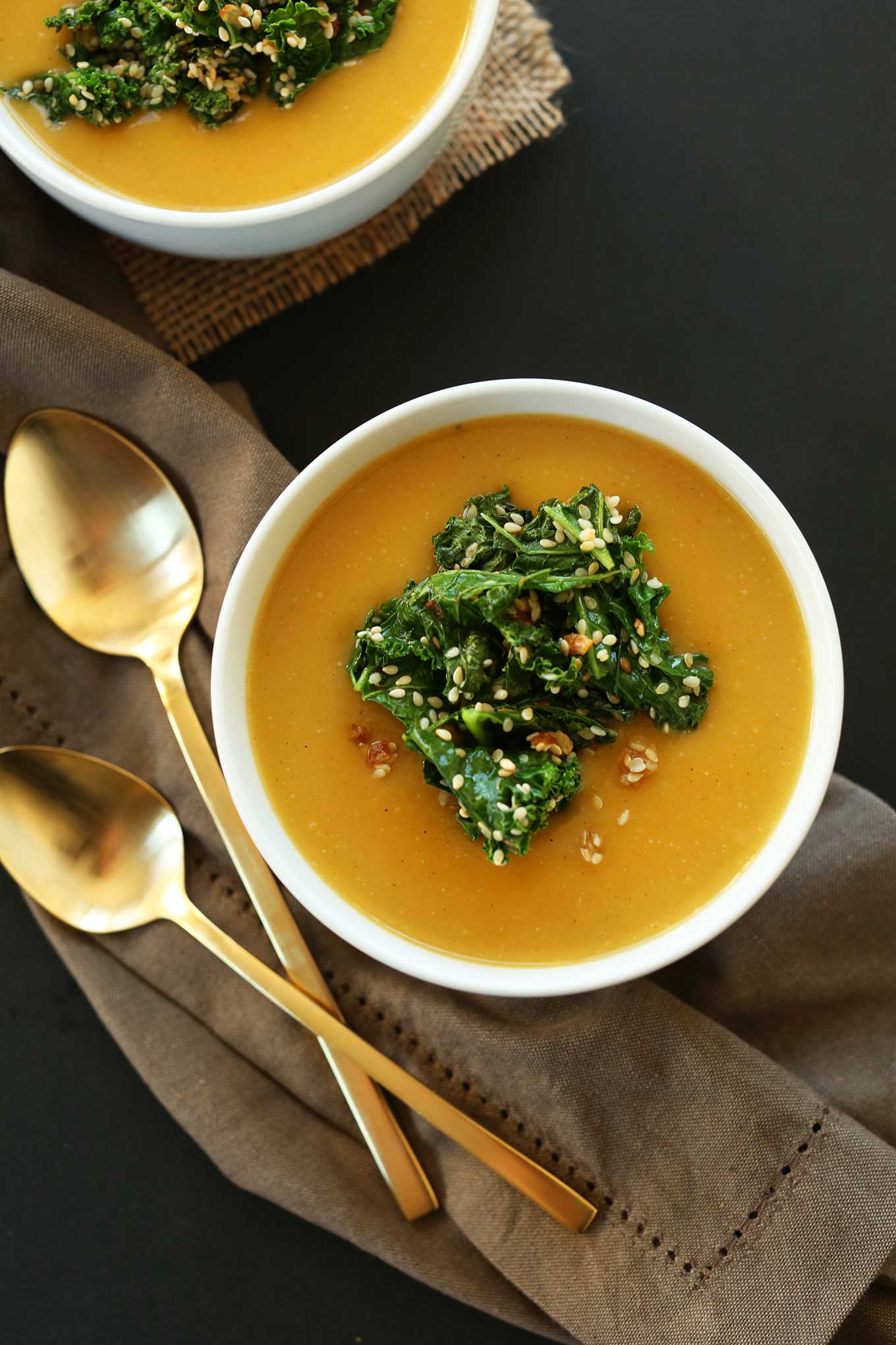 Overhead shot of bowls of gluten-free vegan pumpkin soup with sesame kale topping