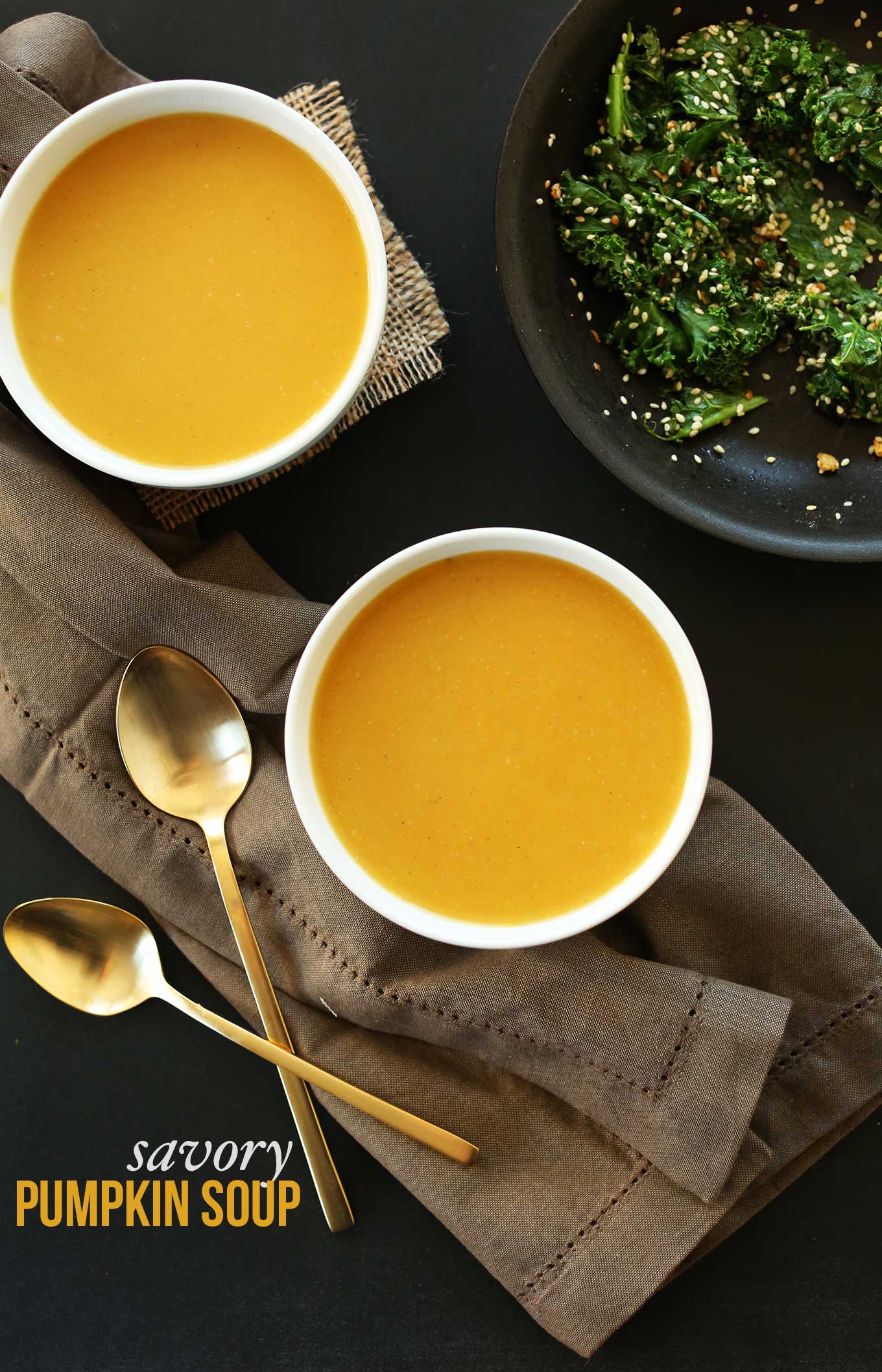 Bowls of simple pumpkin soup alongside a pan of sesame kale