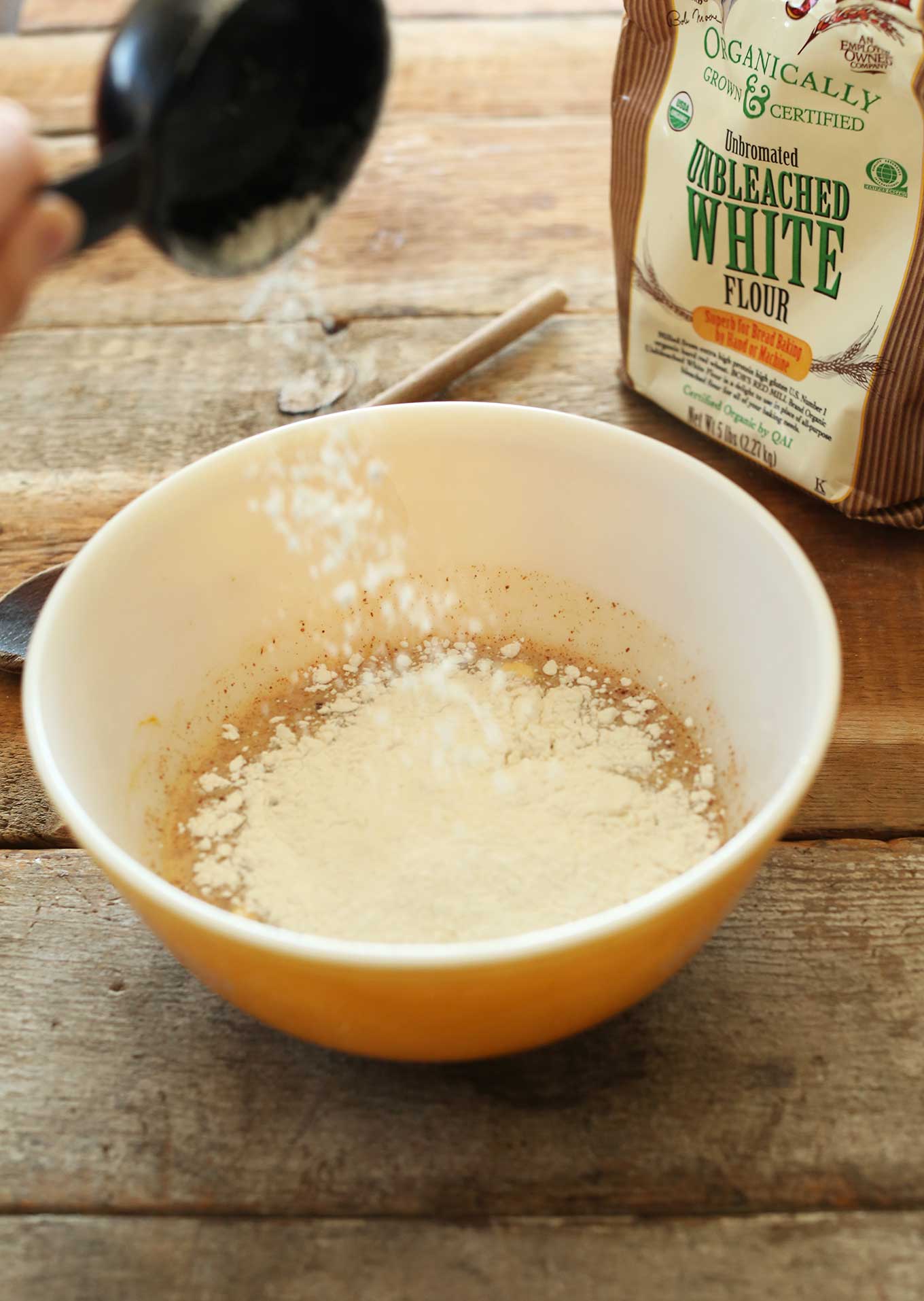 Pouring flour into the dough for making our Vegan Pumpkin Cinnamon Rolls recipe