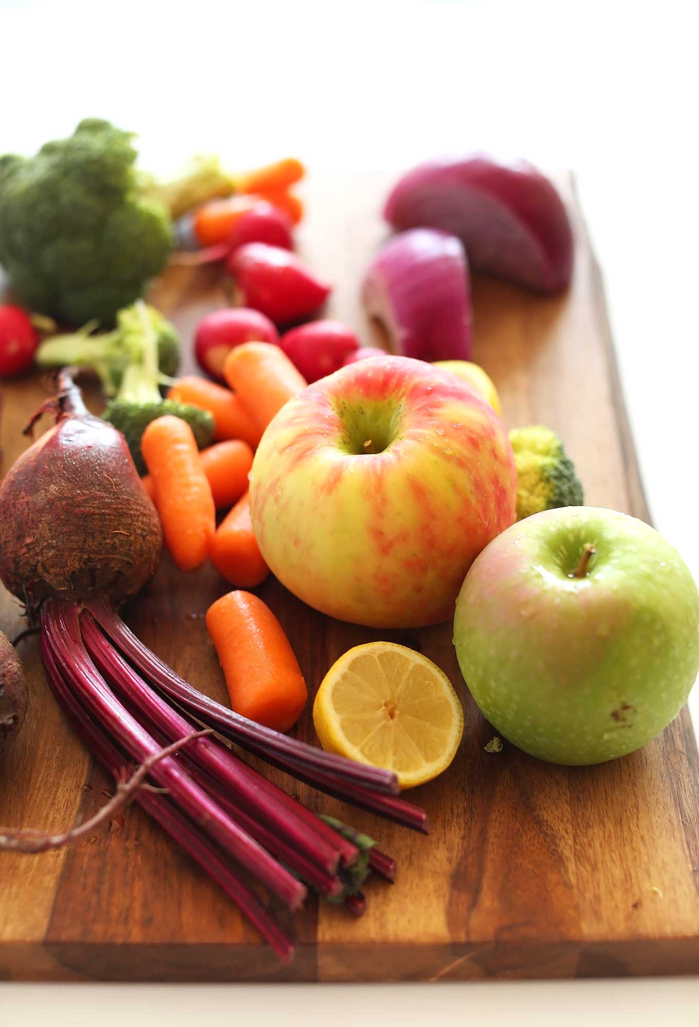 Fresh apples, carrots, beets, broccoli, radish, onions, and lemon for making a healthy fall slaw