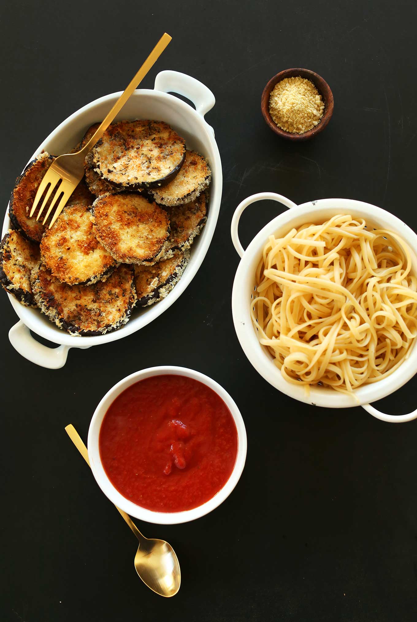 Dishes of marinara, pasta, vegan parmesan, and vegan eggplant parmesan for a comforting meal